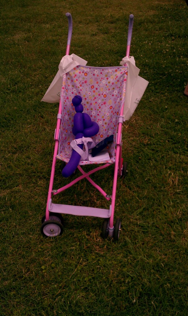 A child parked her balloon animal in her stroller while she played with a hoop.